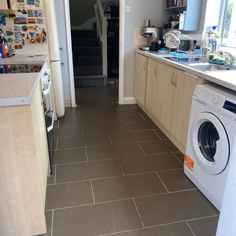 Clean Kitchen A clean modern kitchen with wooden cabinets, washing machine, and tiled flooring.