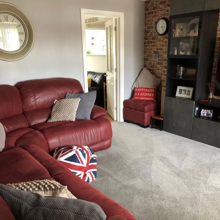 Clean Living Room A cosy living room with red leather sofas, a clock, and a British flag cushion.