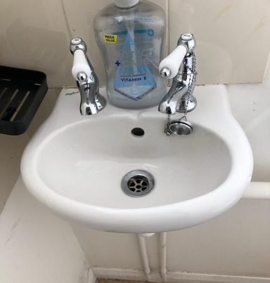 Small white sink with chrome taps and a soap dispenser above it.