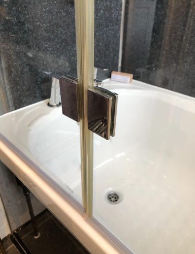 White bathtub with a glass shower screen and a modern tap fixture.