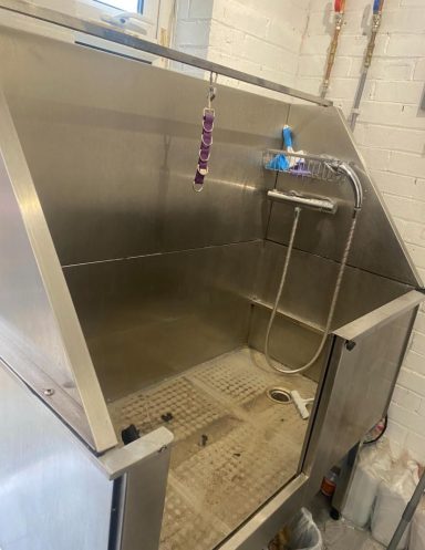 Stainless steel utility tub with a faucet and adjustable spray nozzle.