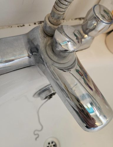 Shiny chrome tap with a single lever in a bathroom sink setting.